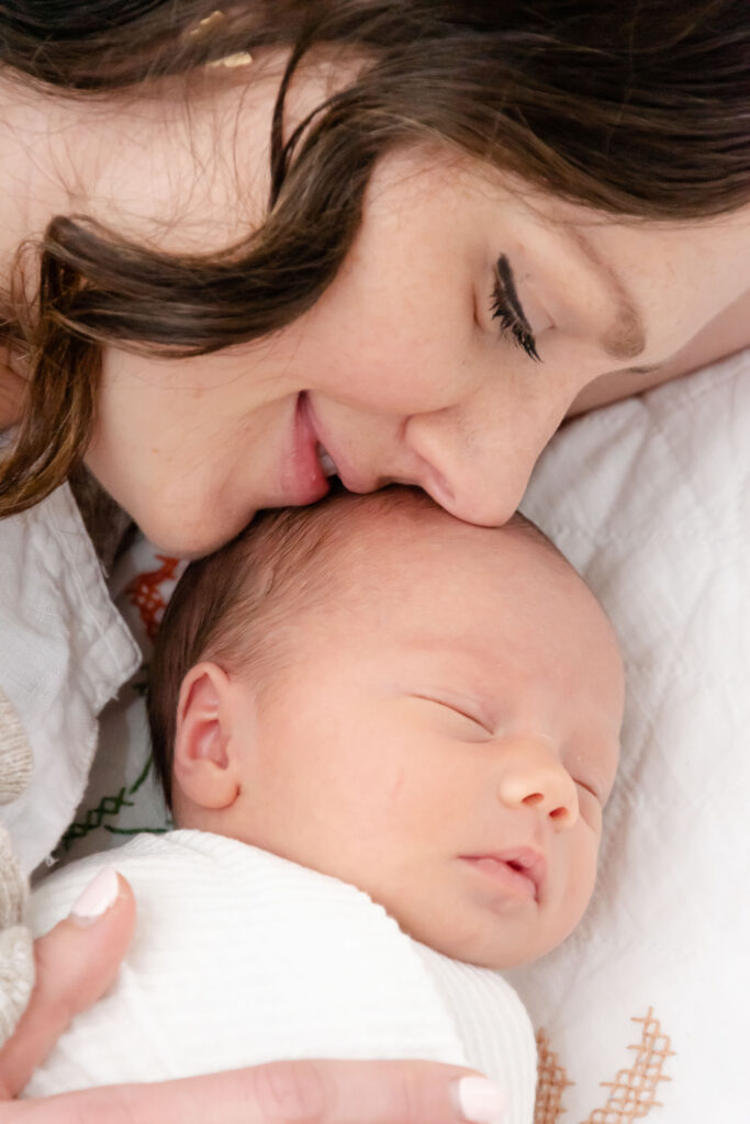 mom and newborn baby laying on bed.