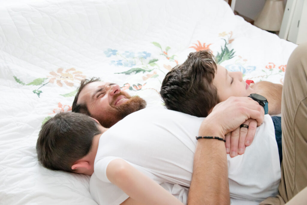 dad and two sons wrestling on the bed.