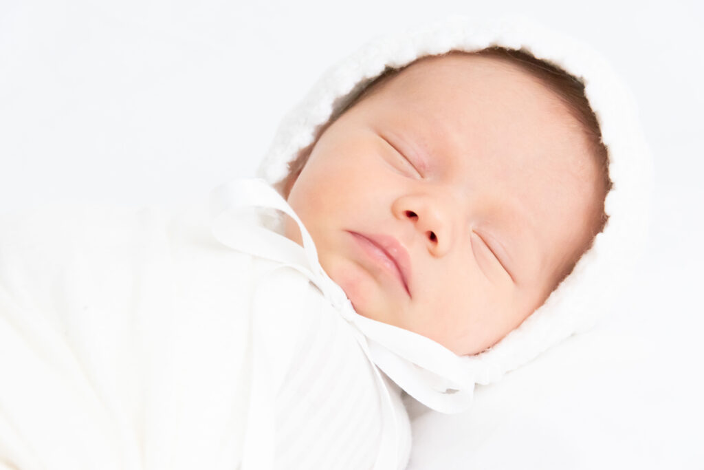 newborn in a white bonnet