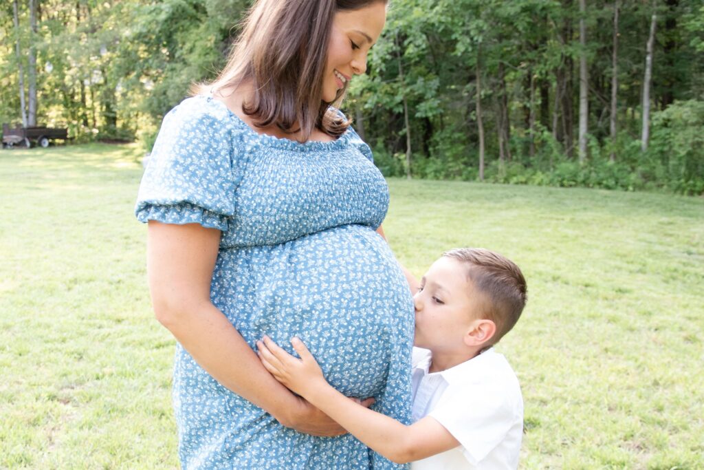 Son kissing his mothers maternity belly.