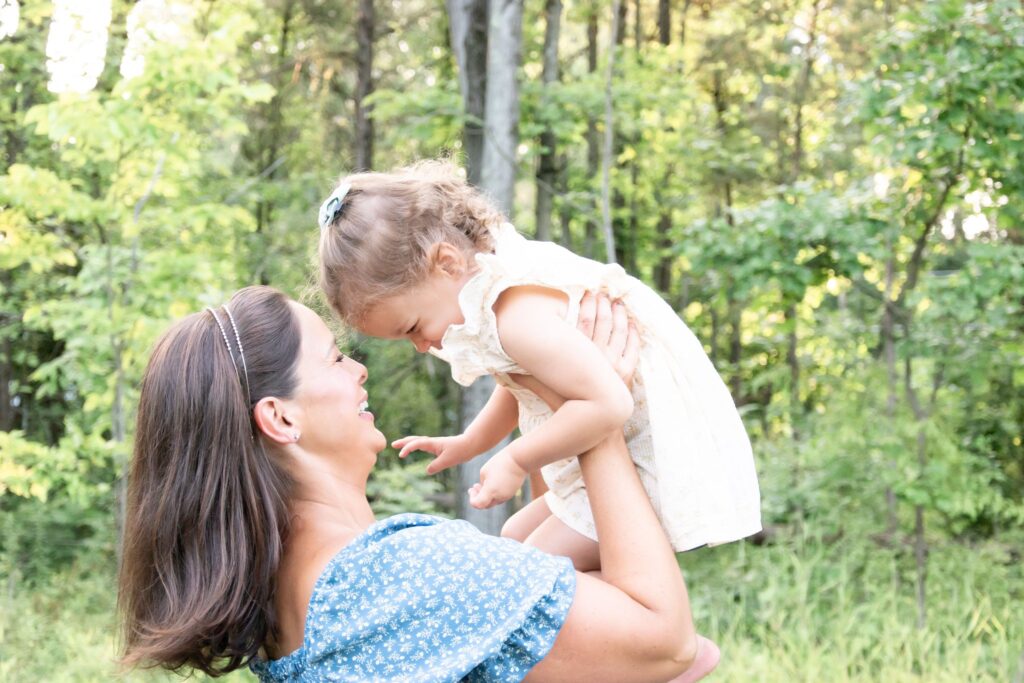 Bright image of a mom and  daughter with her daughter lifted above her head.