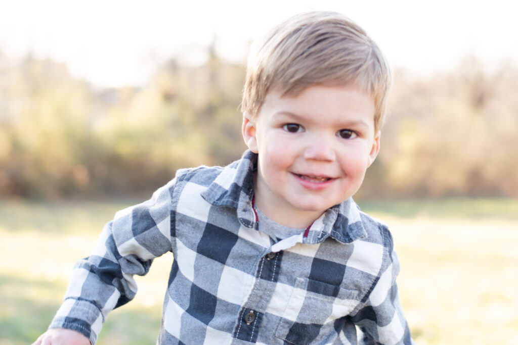 Little boy smiling in a black and white checkered shirt.