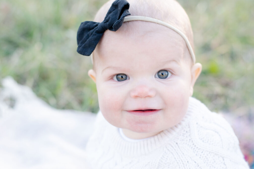 Baby looking at camera in white sweater.