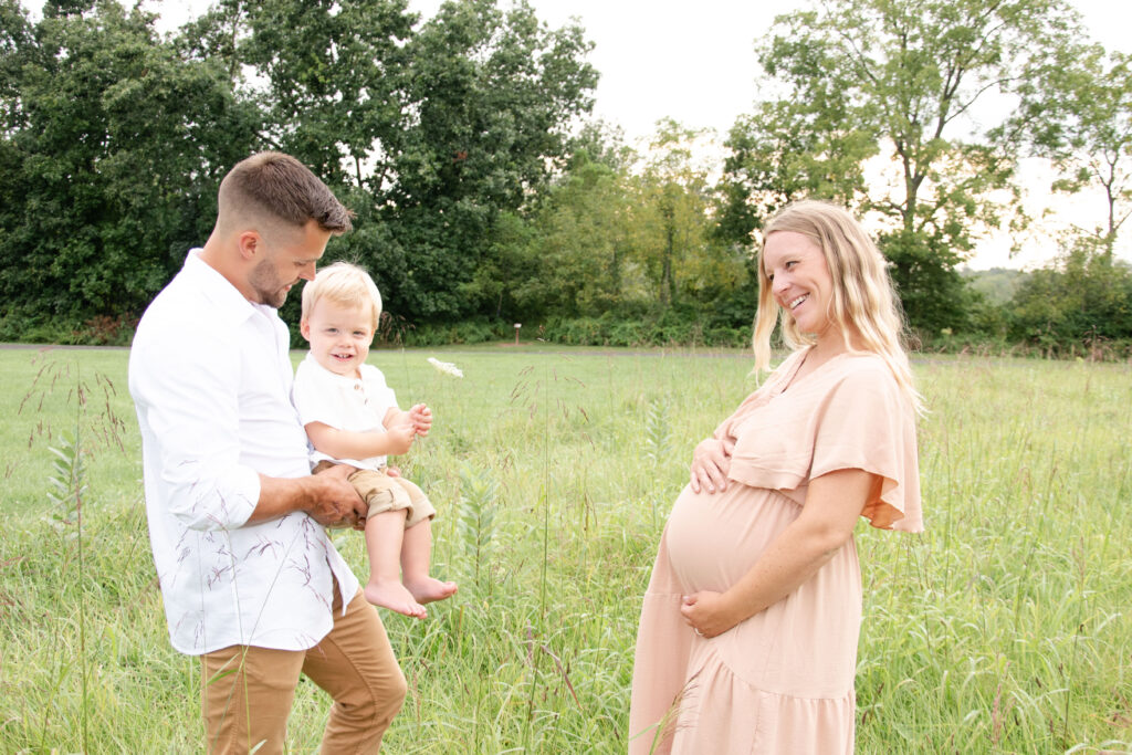 Maternity Session with a young boy handing his mother flowers. A maternity session with a light pink dress.