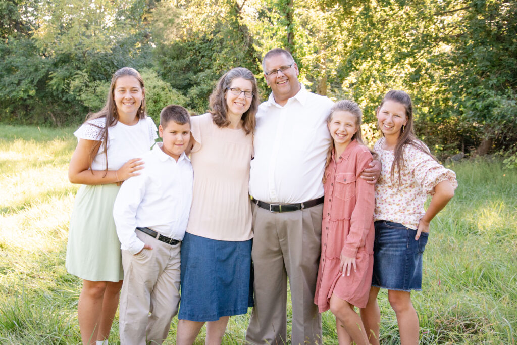 Family standing together posing for a picture. mom, dad, brother, and three sisters.