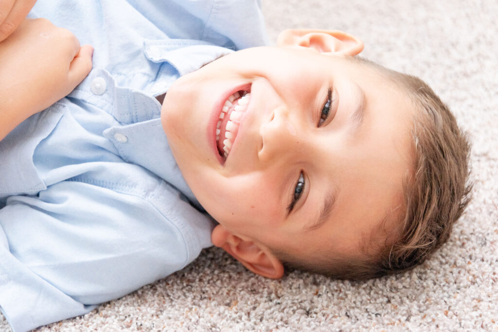 Boy smiling in blue shirt.