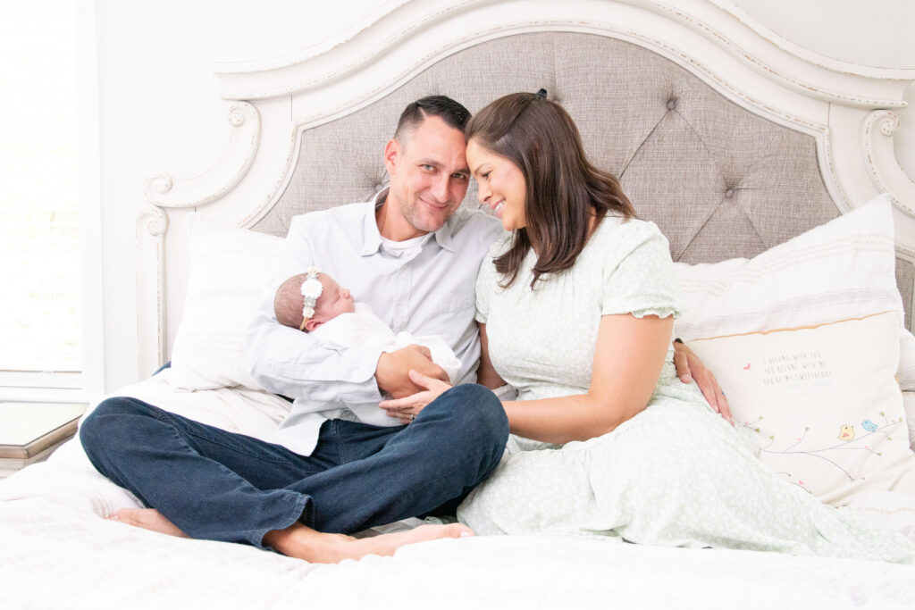Mom and dad on bed looking at newborn baby.
