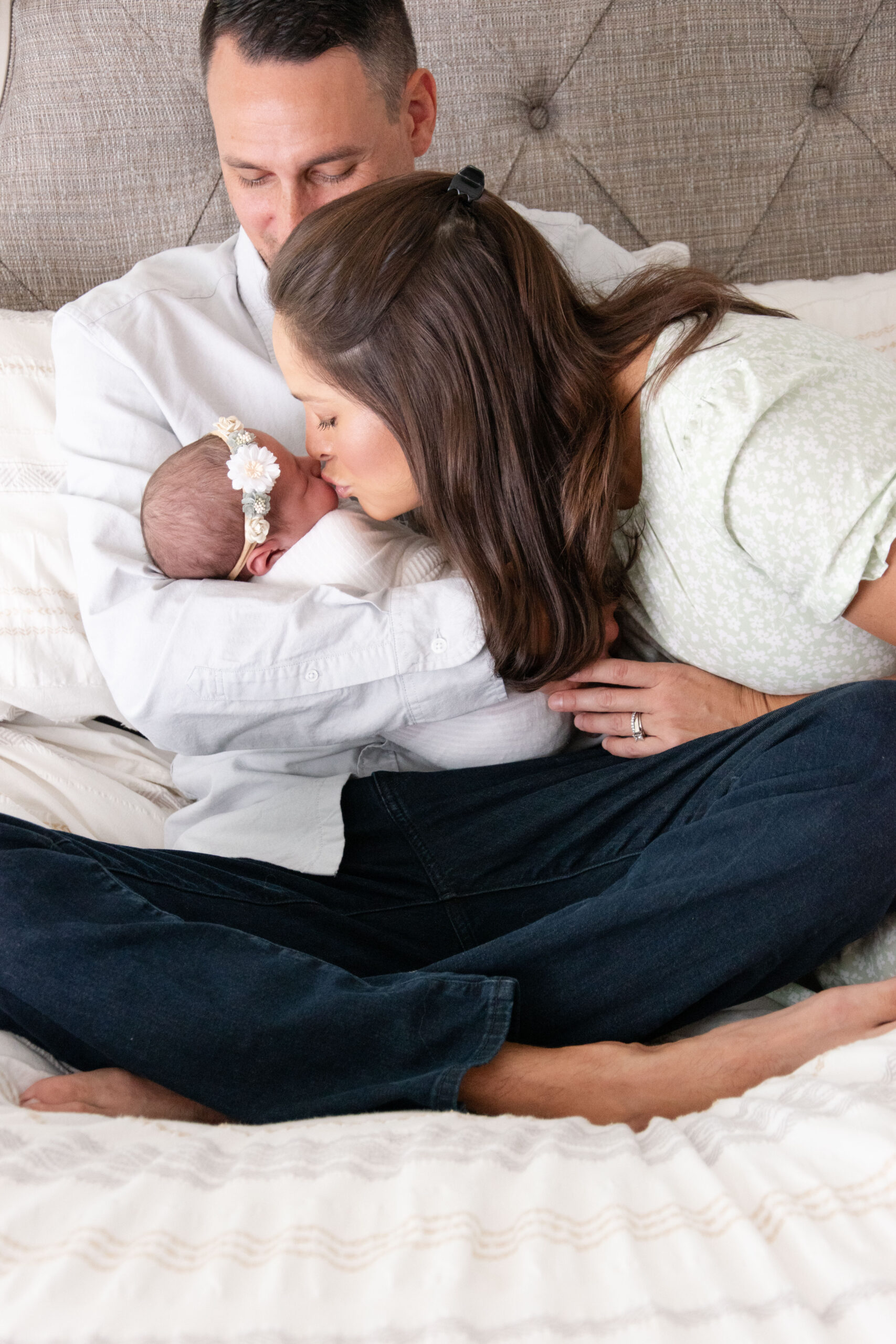 Mom kissing her newborn baby that is swaddled in a white blanket. Graterford newborn photographer