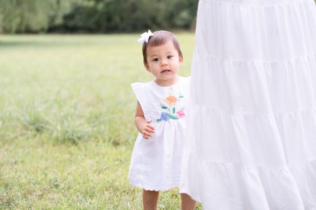 Young toddler wearing white dress.