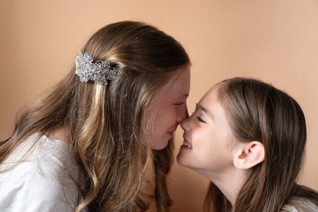 Sisters rubbing noses with a silver clip for the brand shoot.