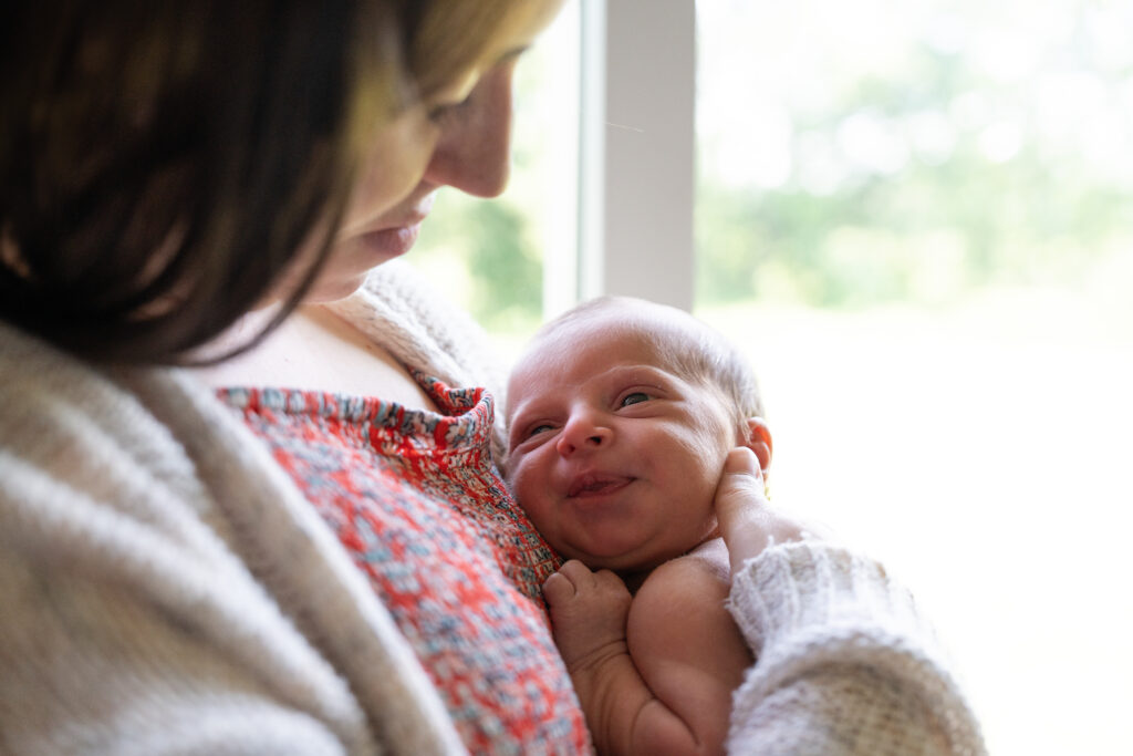 Newborn with his eyes open in his mom's arms.
