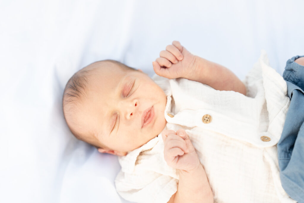 Newborn baby laying on a white blanket.
