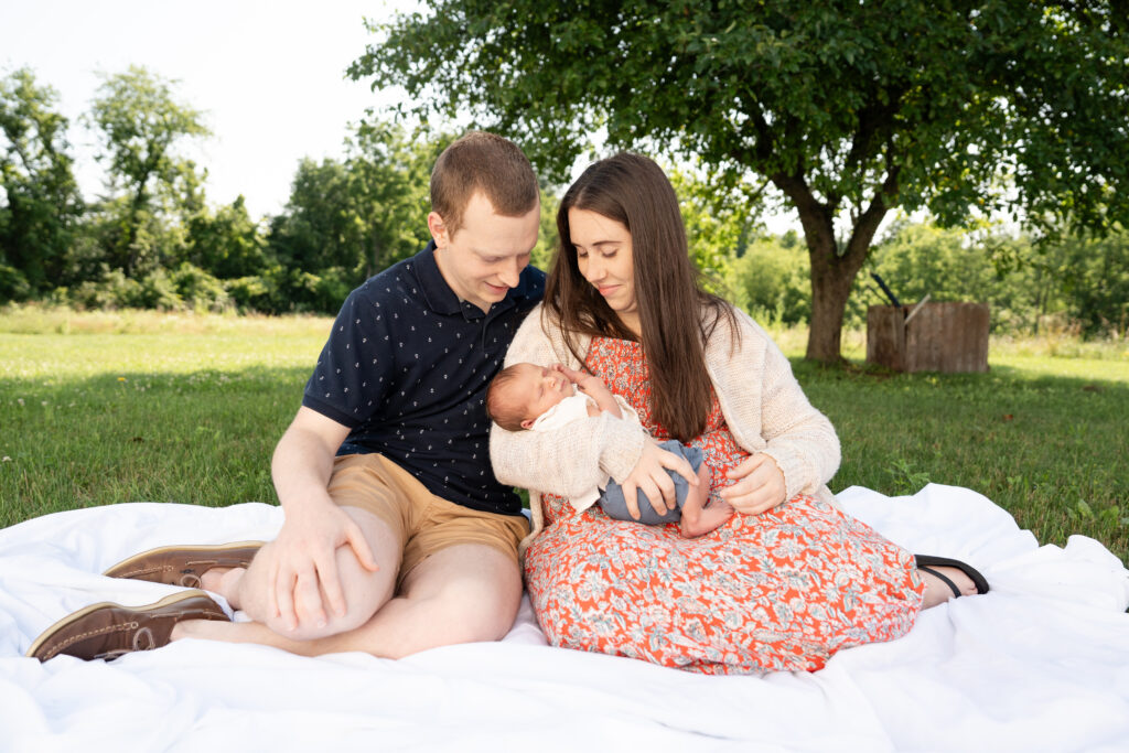 Newborn with new parents outside. 