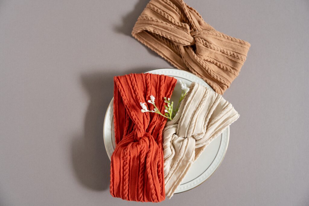 Three headbands with white flowers on a white plate and grey background.