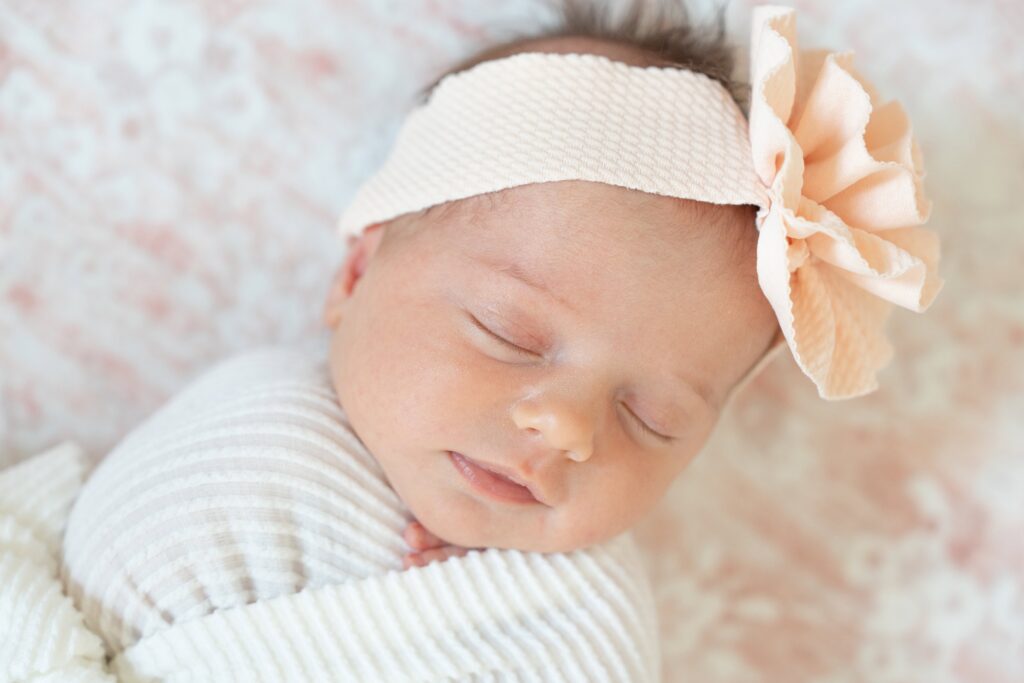 Sleeping newborn with pink headband and flower.